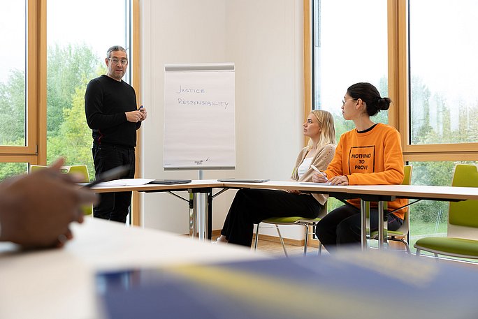 Ein Professor und zwei Studierende sitzen im Seminar im Studiengang PPÖ (B. A.).