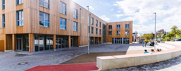 Picture of a wooden building with forecourt in the sun