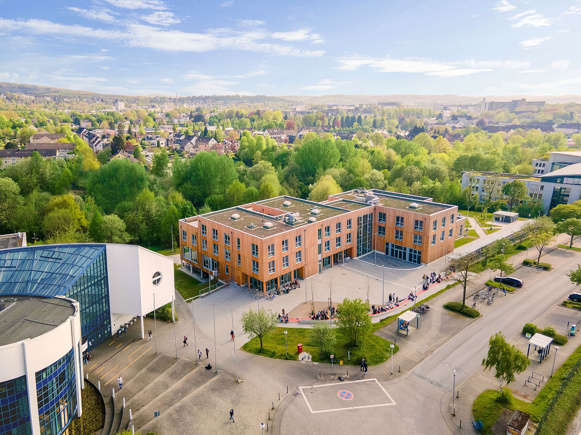 Drohnenaufnahme des Holzgebäudes der Universität Witten/Herdecke mitten im Grünen