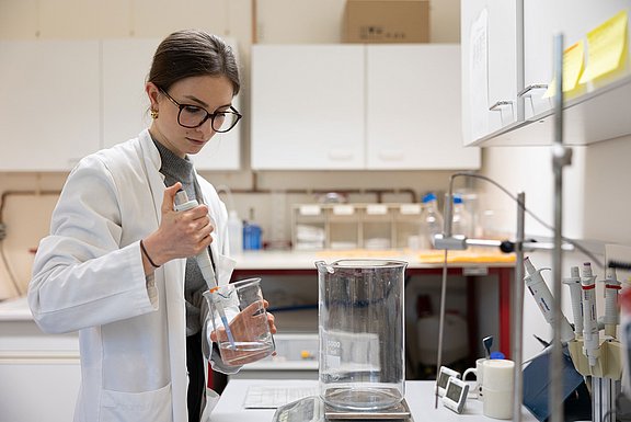 A young woman is standing in a laboratory carrying out tests.