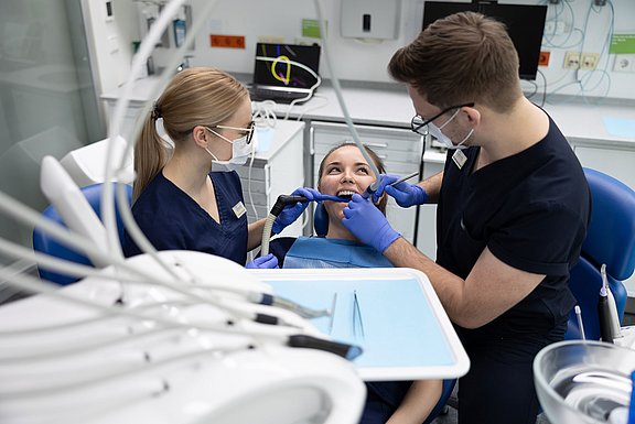 Zwei zahnmedizinische Fachangestellte arbeiten an einer Patientin.