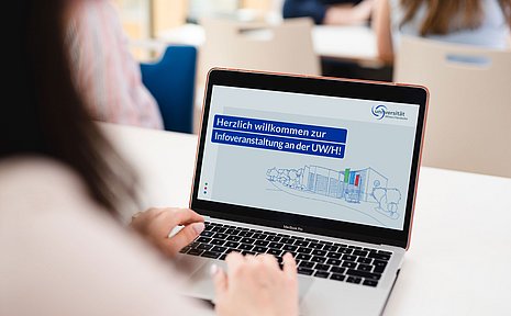 Screen eines Laptops, auf dem "Herzlich willkommen zur Infoveranstaltung an der UW/H" zu lesen ist 