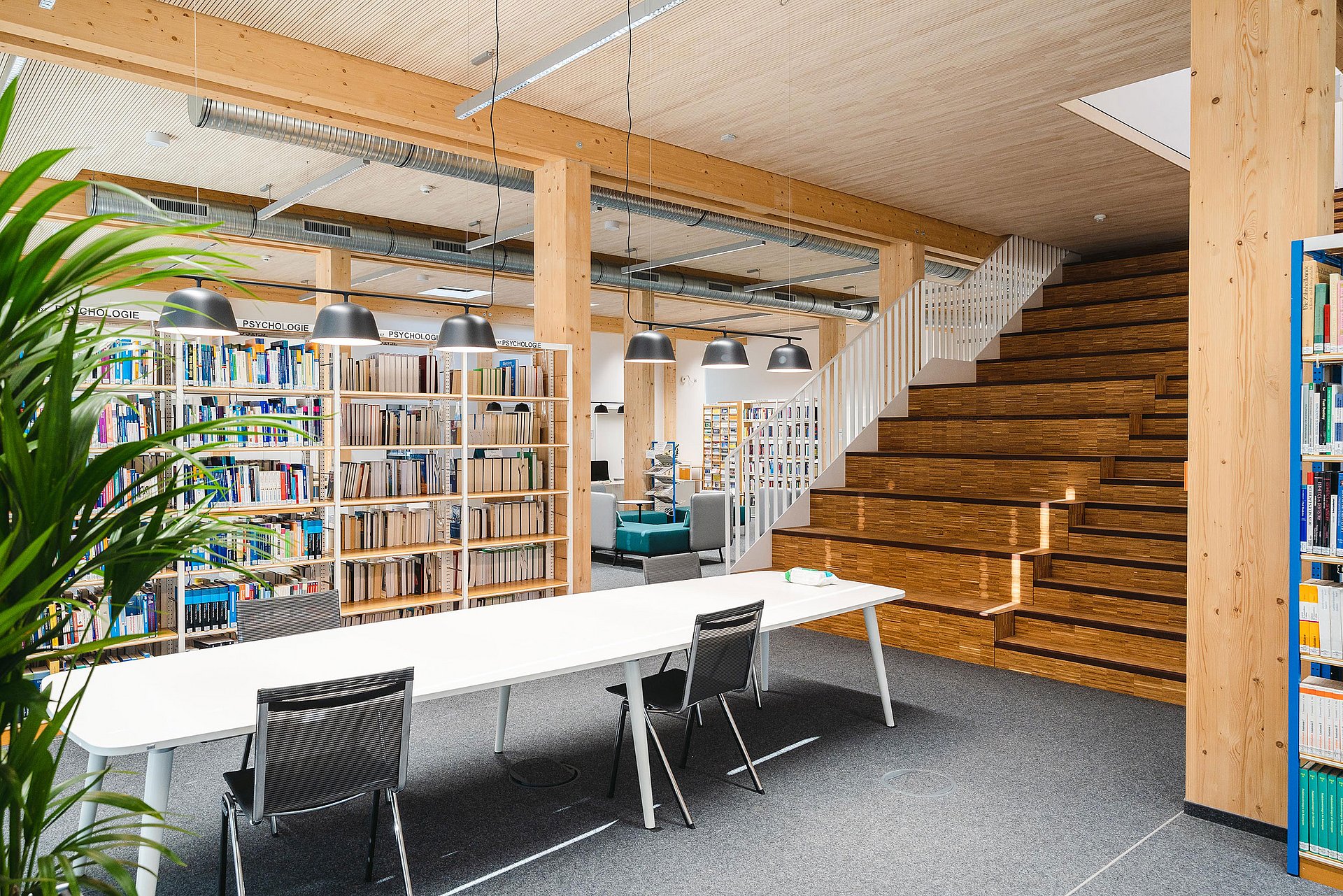 Decorative picture of a library with tables and chairs in the foreground and bookshelves in the background