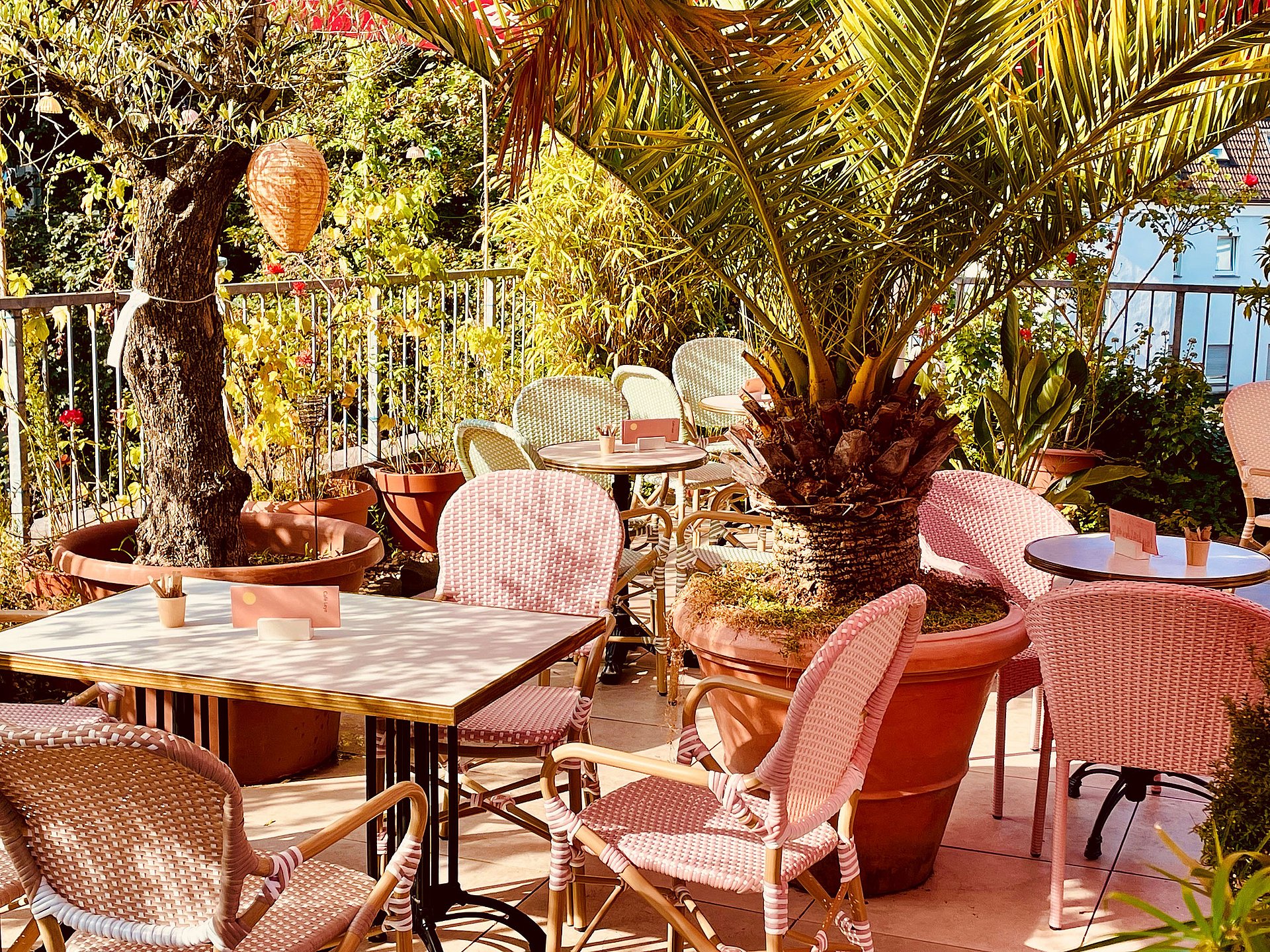 Foto einer begrünten Restaurant-Terrasse mit Tisch- und Stuhlgruppen.