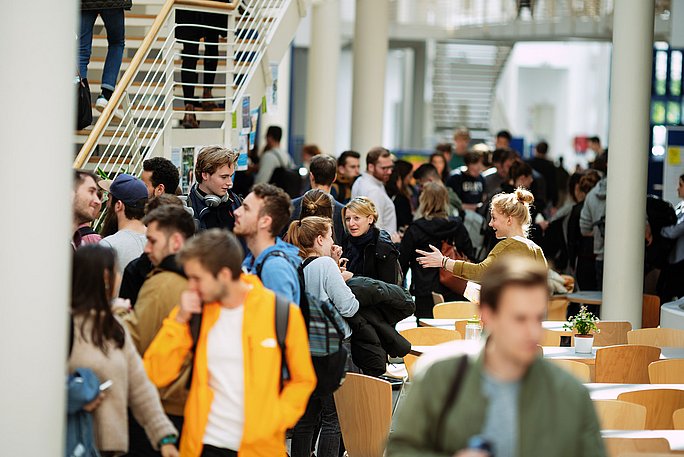 Foto von zahlreichen Studierenden, die durch die Campushalle laufen.