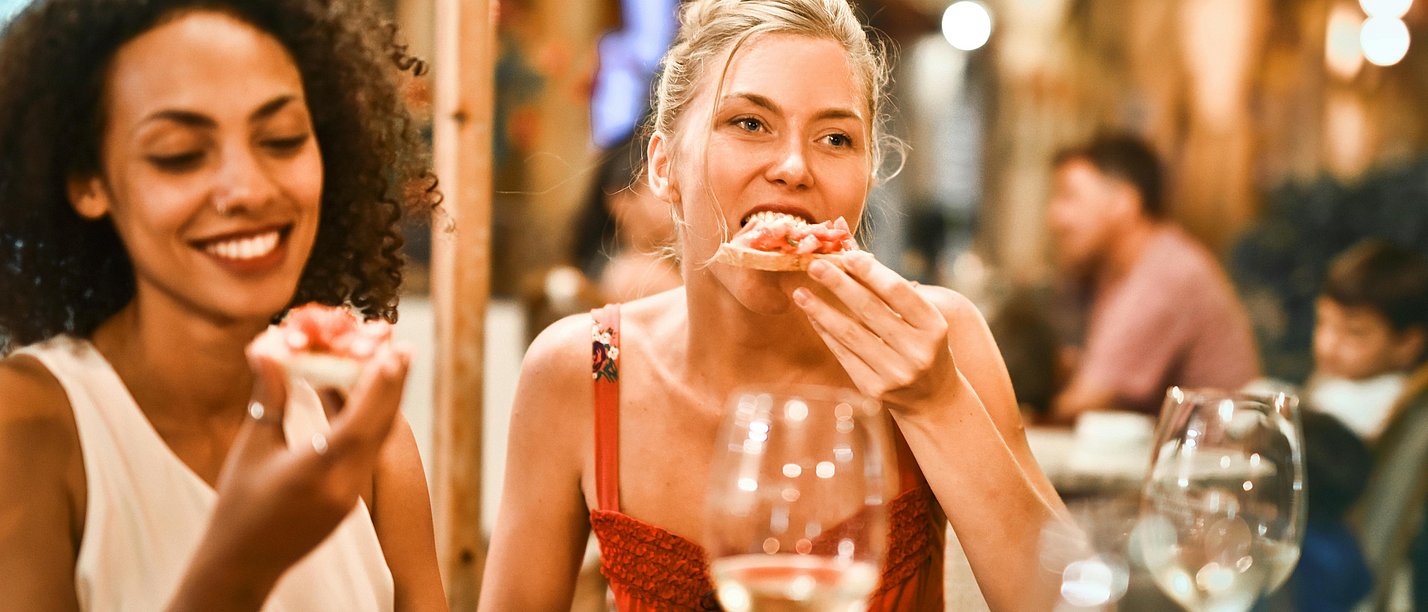 Two women having dinner. They are sitting at a restaurant table.