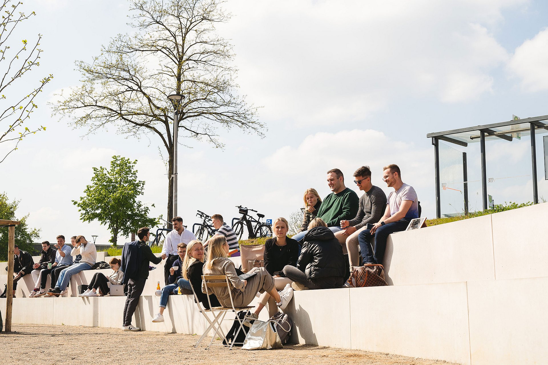 Studierende sitzen auf Treppenstufen draußen auf dem Vorplatz der Universität Witten/Herdecke