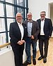 Three men in suits smile at the camera and are happy about the co-operation.