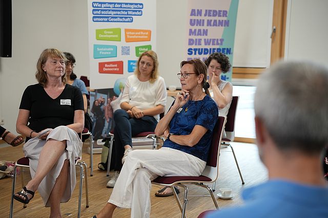 Dr. Beate Stock-Schröer spricht mit Prof. Dr. Petra Thürmann. Teilnehmende im Hintergrund zu sehen.