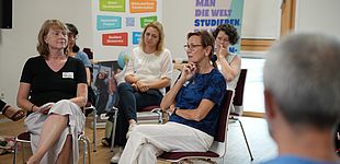 Dr. Beate Stock-Schröer spricht mit Prof. Dr. Petra Thürmann. Teilnehmende im Hintergrund zu sehen.