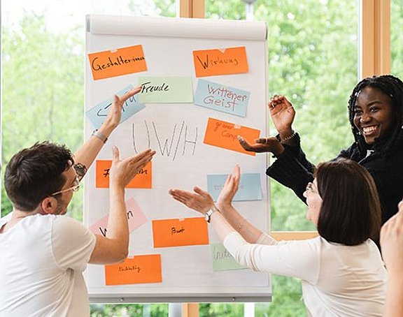 Studierende mit Flipchart beschreiben den Vibe an der UW/H.