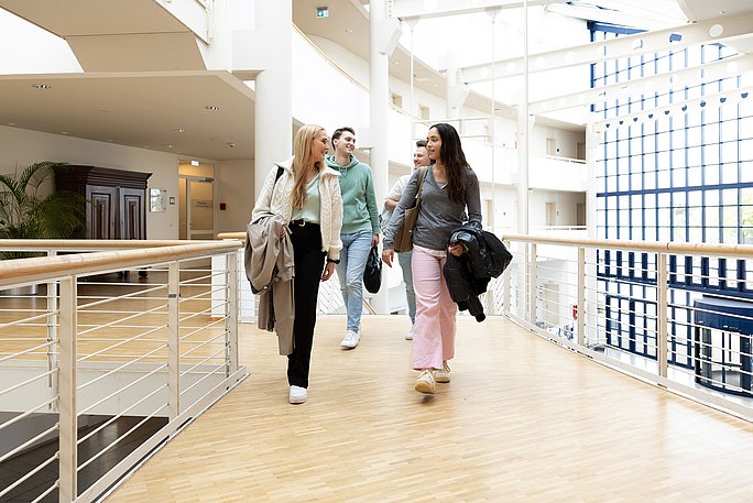 Studierende laufen zum Seminar im weiß-blauen Gebäude der UW/H.