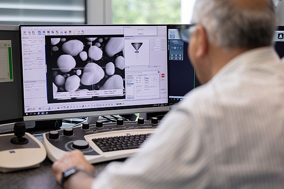 View over the shoulder of a man looking at research data on a screen.