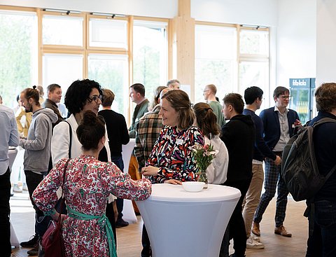 Veranstaltungsfoto: Mehrere Personen in Gesprächssituationen in einem Festsaal.