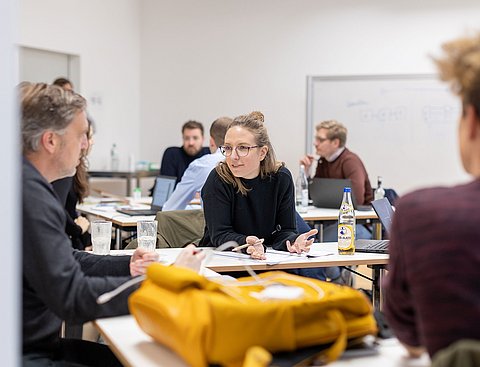 Teilnehmer eines Lehrgangs des Professional Campus sind im Gespräch an Stehtischen.