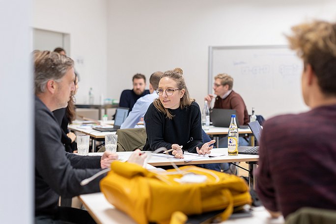 Teilnehmer eines Lehrgangs des Professional Campus sind im Gespräch an Stehtischen.