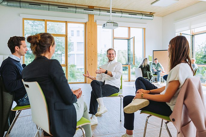 Teilnehmer:innen des berufsbegleitenden Studiums Witten MBA sitzen sich gegenüber und sind im Gespräch.