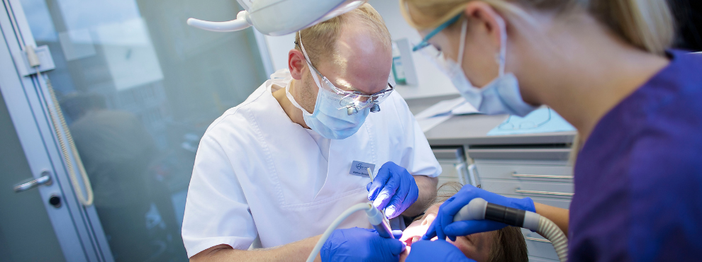 A dentist performs a treatment on his patient.