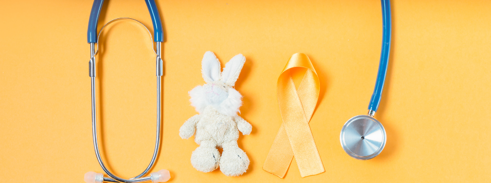 A stethoscope, a golden bow and a fabric bunny can be seen on a yellow-gold background.