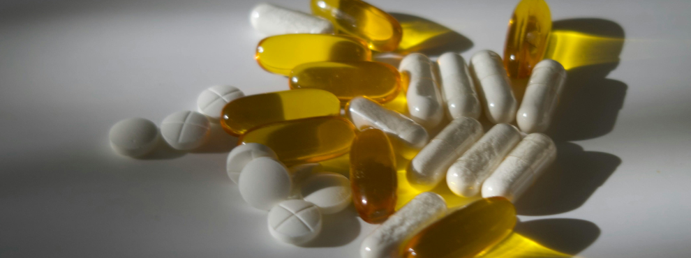 White and yellow tablets and pills lie on a table.