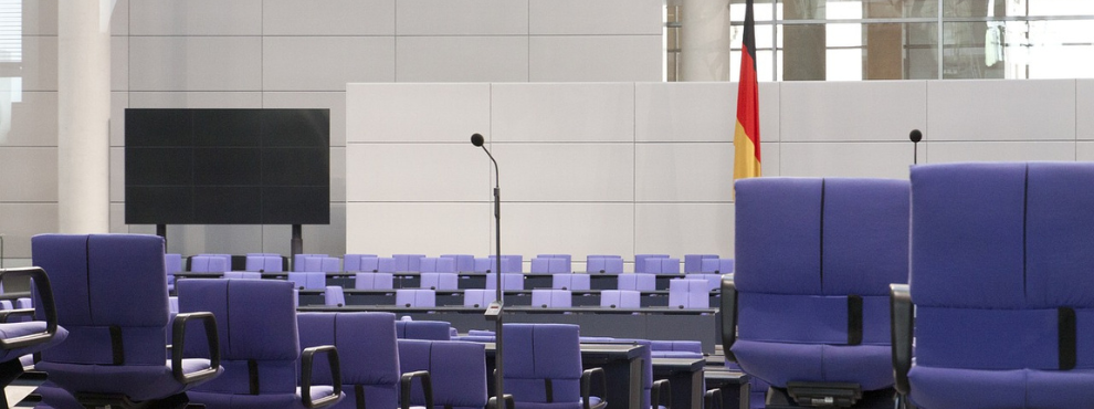 Blick auf die Sitze des leeren Bundestages. Im Hintergrund ist eine Deutschlandflagge.