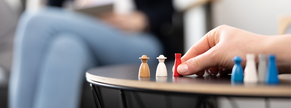 One hand moves game pieces standing on a table.