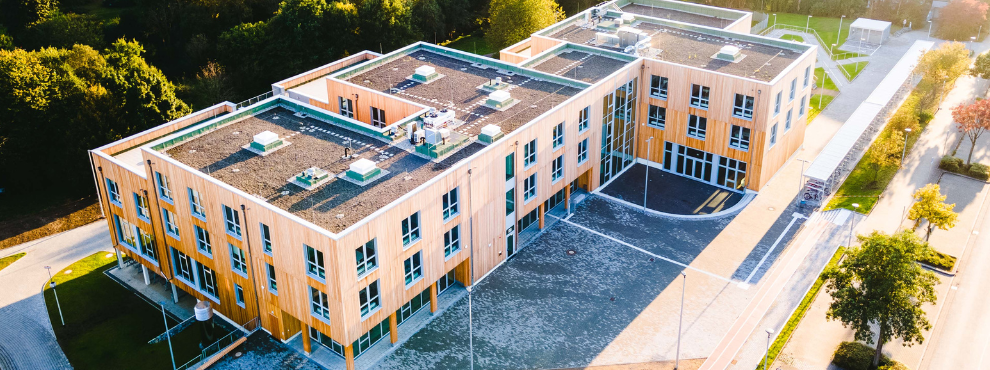 Luftaufnahme des UW/H-Campus. Im Fokus sind der Holzbau und der Campus-Vorplatz.